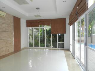 Bright living room with large windows and glass doors opening to a patio with a pool