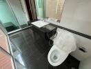 Modern bathroom with glass shower and black-tiled floor