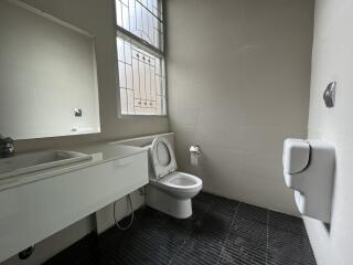 Modern bathroom with a toilet, sink, and large window