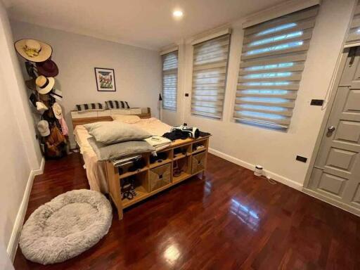 Well-lit bedroom with wooden flooring and multiple windows