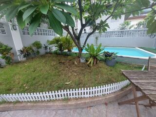 well-maintained garden with a small tree, plants, and a swimming pool