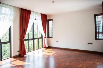 Spacious living room with large windows, wooden floor, and curtains