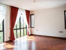 Spacious living room with large windows, wooden floor, and curtains