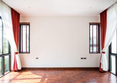 Bright living room with large windows, wooden flooring, and red curtains