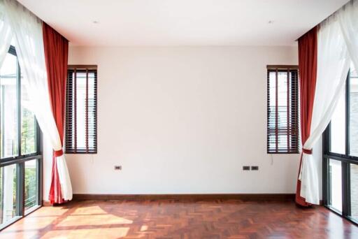 Bright living room with large windows, wooden flooring, and red curtains