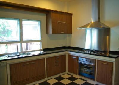 Modern kitchen with wooden cabinets, stainless steel appliances, and large window