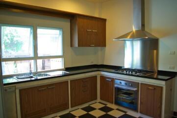 Modern kitchen with wooden cabinets, stainless steel appliances, and large window