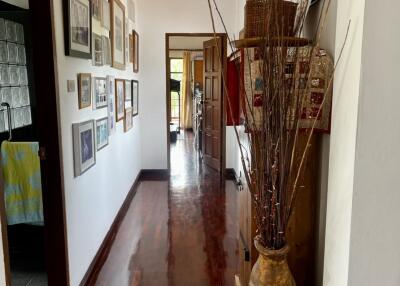 A decorated hallway with wooden flooring and picture frames on the wall.