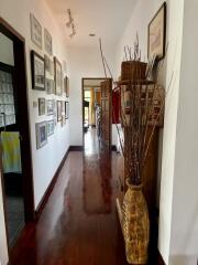 A decorated hallway with wooden flooring and picture frames on the wall.