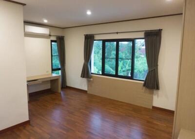 Spacious bedroom with wooden flooring and large windows