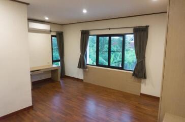 Spacious bedroom with wooden flooring and large windows