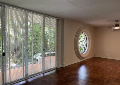 Spacious living room with large circular window and floor-to-ceiling blinds