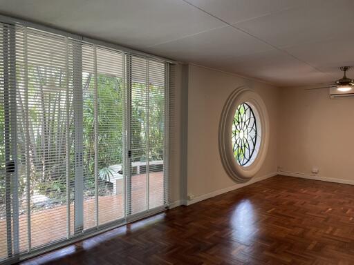 Spacious living room with large circular window and floor-to-ceiling blinds