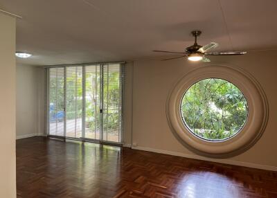 Spacious living room with large circular window and parquet flooring