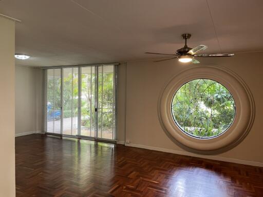 Spacious living room with large circular window and parquet flooring