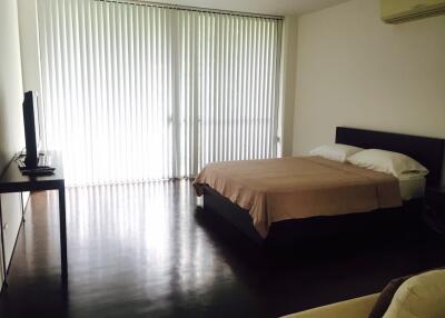 Spacious bedroom with a large bed, TV, and window blinds