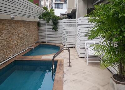 Private outdoor swimming pool area with plants and seating