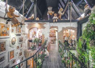 Whimsical interior of a property featuring a suspended bridge adorned with teddy bears and numerous decorative elements