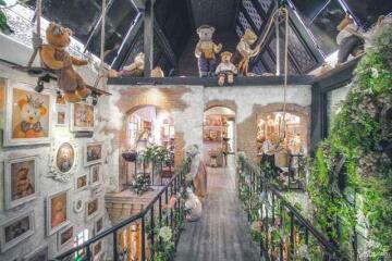 Whimsical interior of a property featuring a suspended bridge adorned with teddy bears and numerous decorative elements