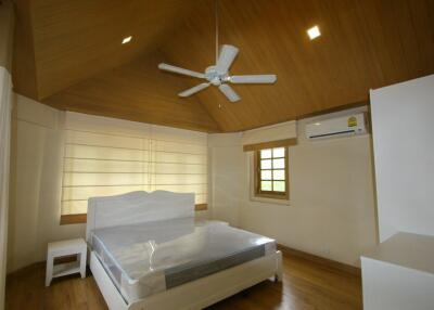 Spacious bedroom with wooden ceiling and fan