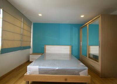 Modern bedroom with blue accent wall, new bed, and wooden wardrobe