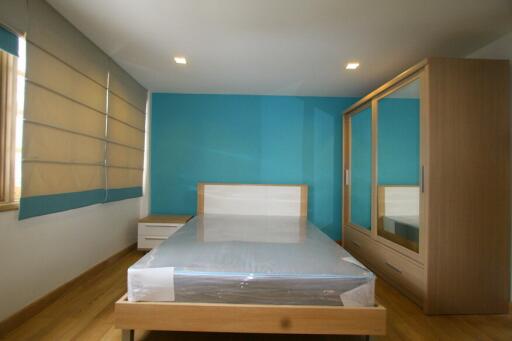 Modern bedroom with blue accent wall, new bed, and wooden wardrobe