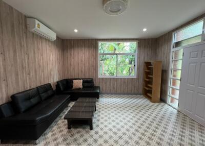 Modern living room with black leather sofa, coffee table, and bookshelf