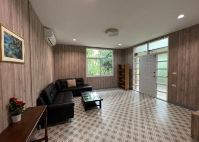 Modern living room with black leather couch and wooden panel walls