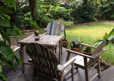 Cozy outdoor seating area with wooden chairs and lush greenery