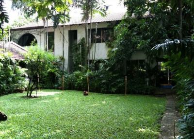 A two-story house surrounded by lush greenery