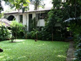 A two-story house surrounded by lush greenery