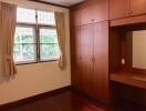 Bedroom with large built-in wooden wardrobe and vanity mirror