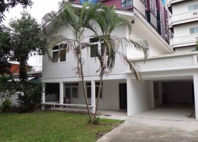 Exterior view of a white two-story house with a carport and front lawn