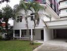 Exterior view of a white two-story house with a carport and front lawn