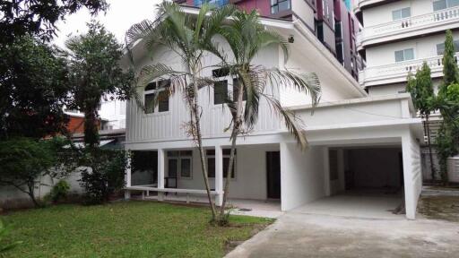 Exterior view of a white two-story house with a carport and front lawn