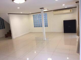 Spacious main living area with polished tiled flooring, large windows, and ceiling lights.