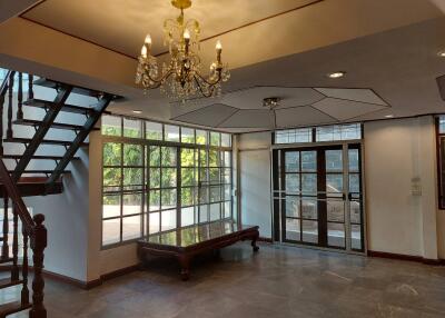 Chandelier-lit living room with large windows and modern staircase