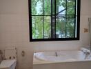 Bathroom with window, bathtub, and toilet