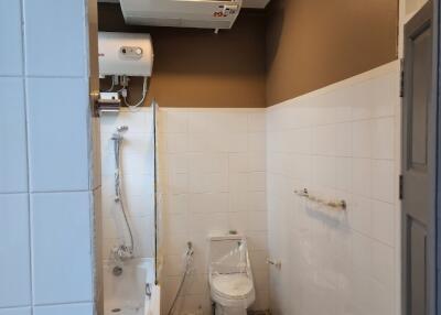 Modern bathroom with white tiles, a shower area, a toilet, and an air conditioning unit