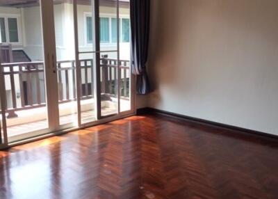 Spacious bedroom with hardwood floors and large windows leading to balcony