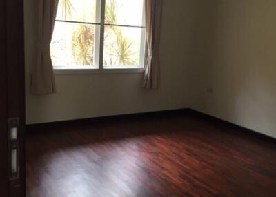 Spacious empty bedroom with wooden flooring and large window