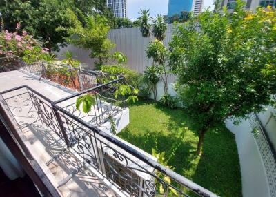 Outdoor balcony view of well-maintained garden with trees and cityscape in the background