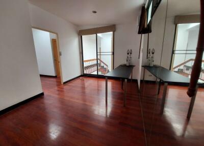 Empty living area with a large mirror, wooden flooring, and a view of the staircase.