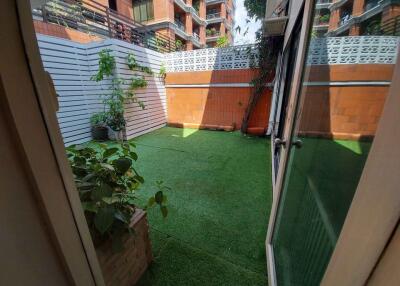 View of a sunny patio with artificial grass and potted plants