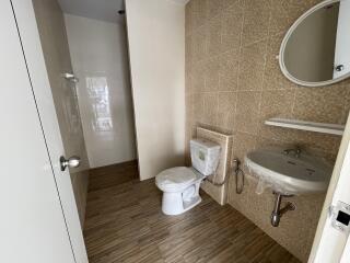 Bathroom with tiled walls and floor, equipped with toilet, sink, and a shower area