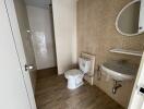 Bathroom with tiled walls and floor, equipped with toilet, sink, and a shower area