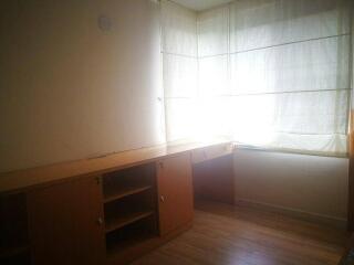 Corner bedroom with built-in wooden desk and large window.