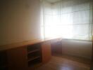 Corner bedroom with built-in wooden desk and large window.