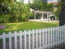 Front yard garden with white picket fence and greenery