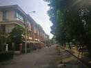 Street view of a residential area with multi-story houses and trees